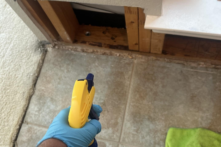 Restoration technician applying antimicrobial treatment to water-damaged surfaces