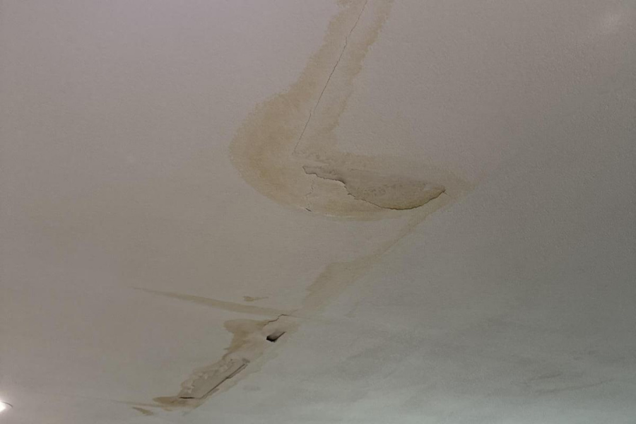 Water-stained ceiling with peeling paint showing damage