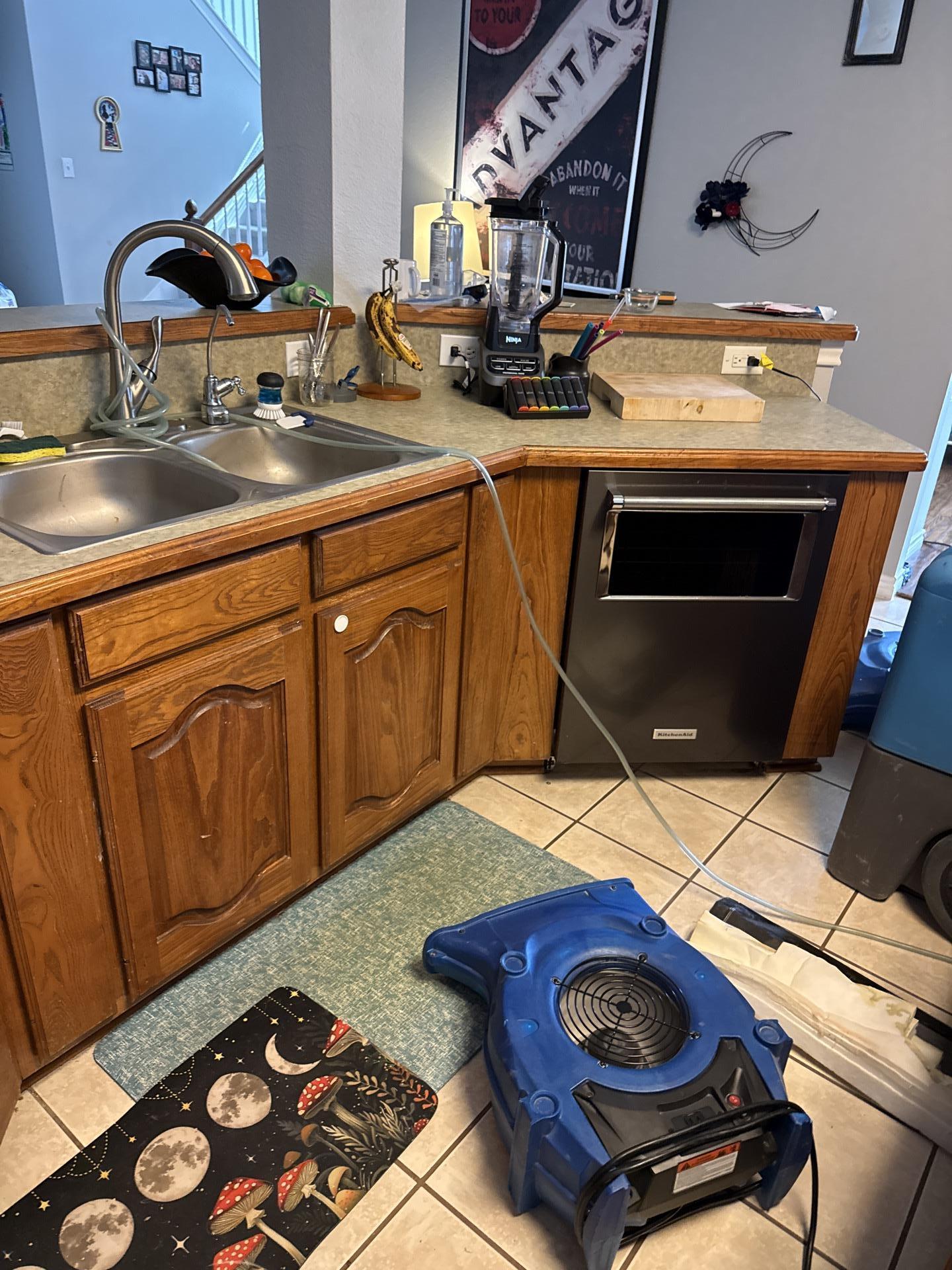 Air movers and dehumidifier working to dry kitchen subfloor after dishwasher leak