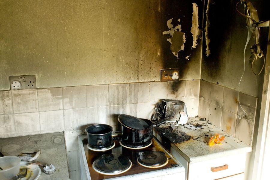 Fire and smoke damage in a kitchen after a cooking fire with soot on walls and cabinets