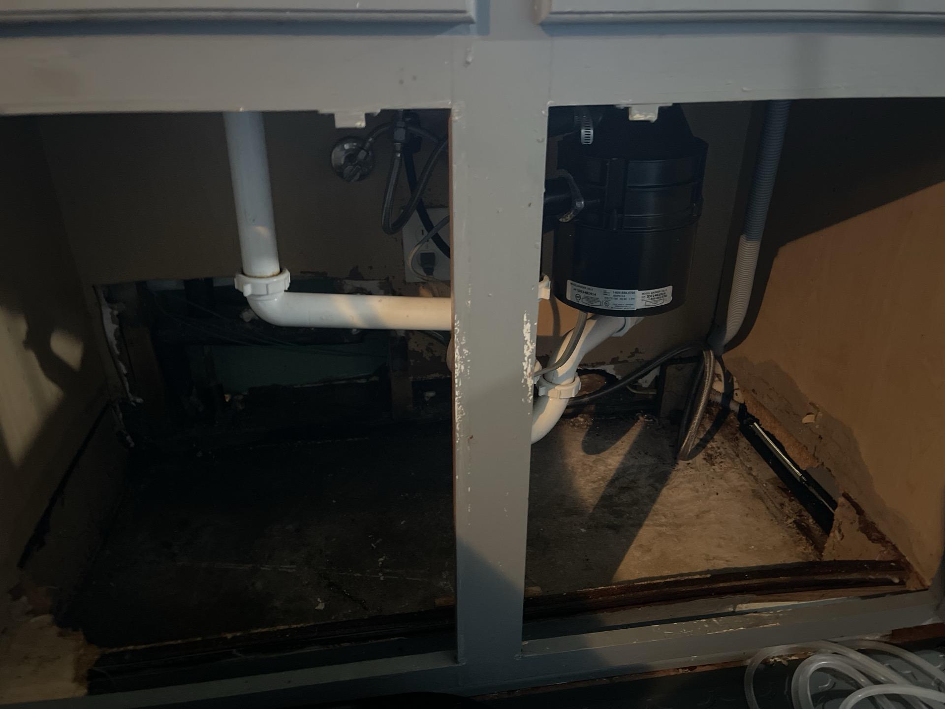 Water-damaged kitchen cabinet base showing warping and discoloration from prolonged moisture exposure