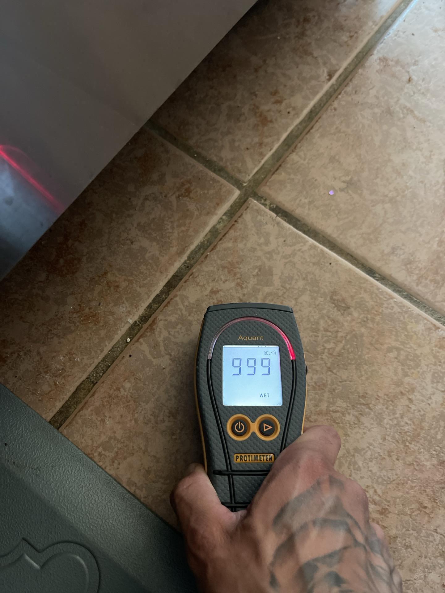 Moisture meter reading taken under kitchen flooring showing elevated moisture levels from sink leak