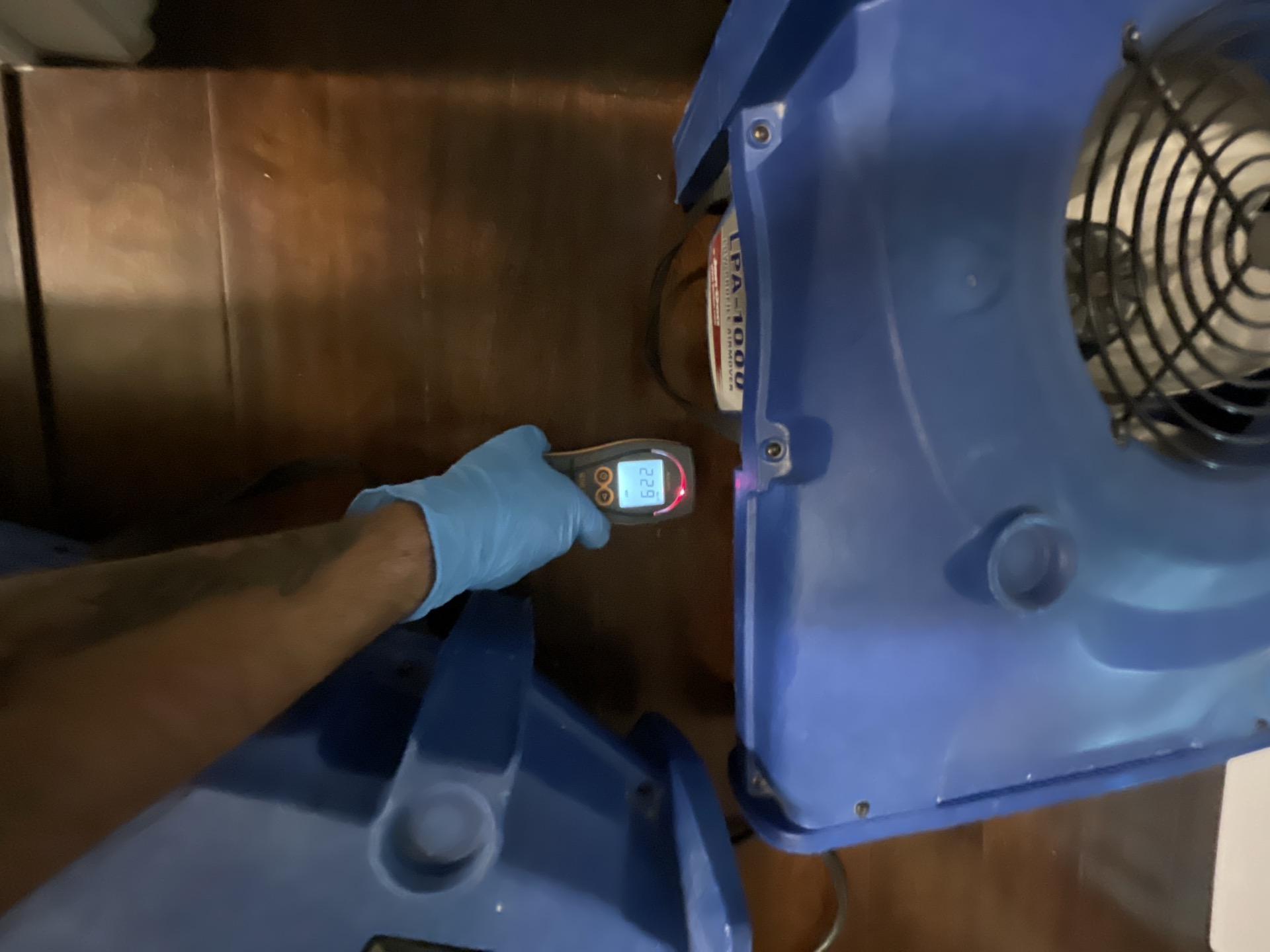 Technician taking moisture readings on hallway hardwood flooring