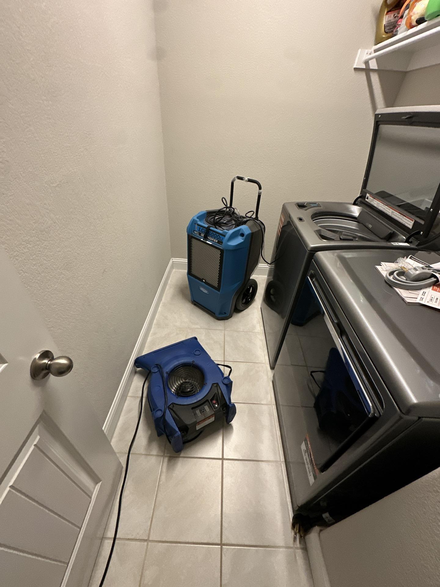 Professional drying equipment set up in laundry room after washing machine leak