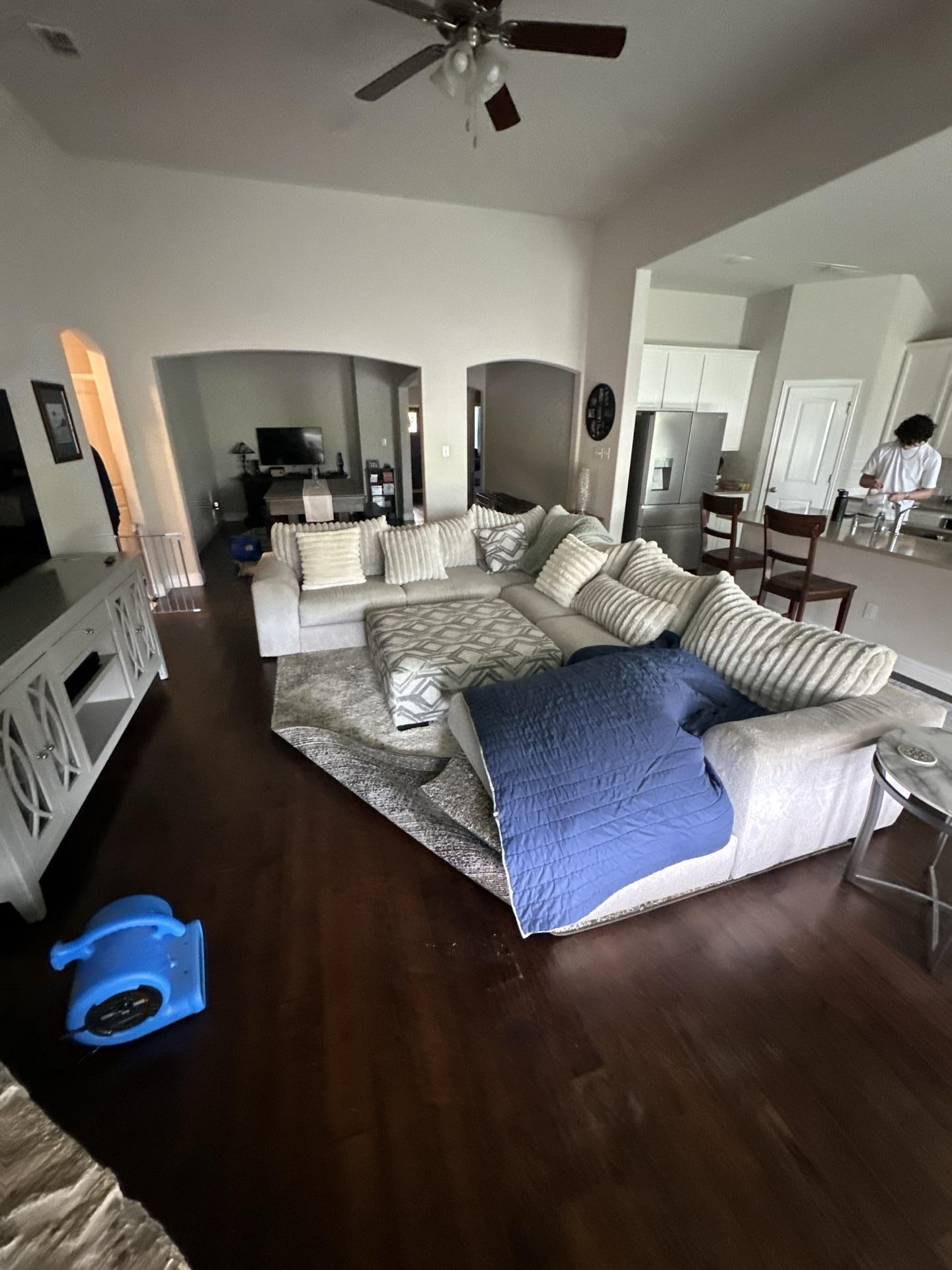 Ongoing water damage restoration in living room showing furniture protection