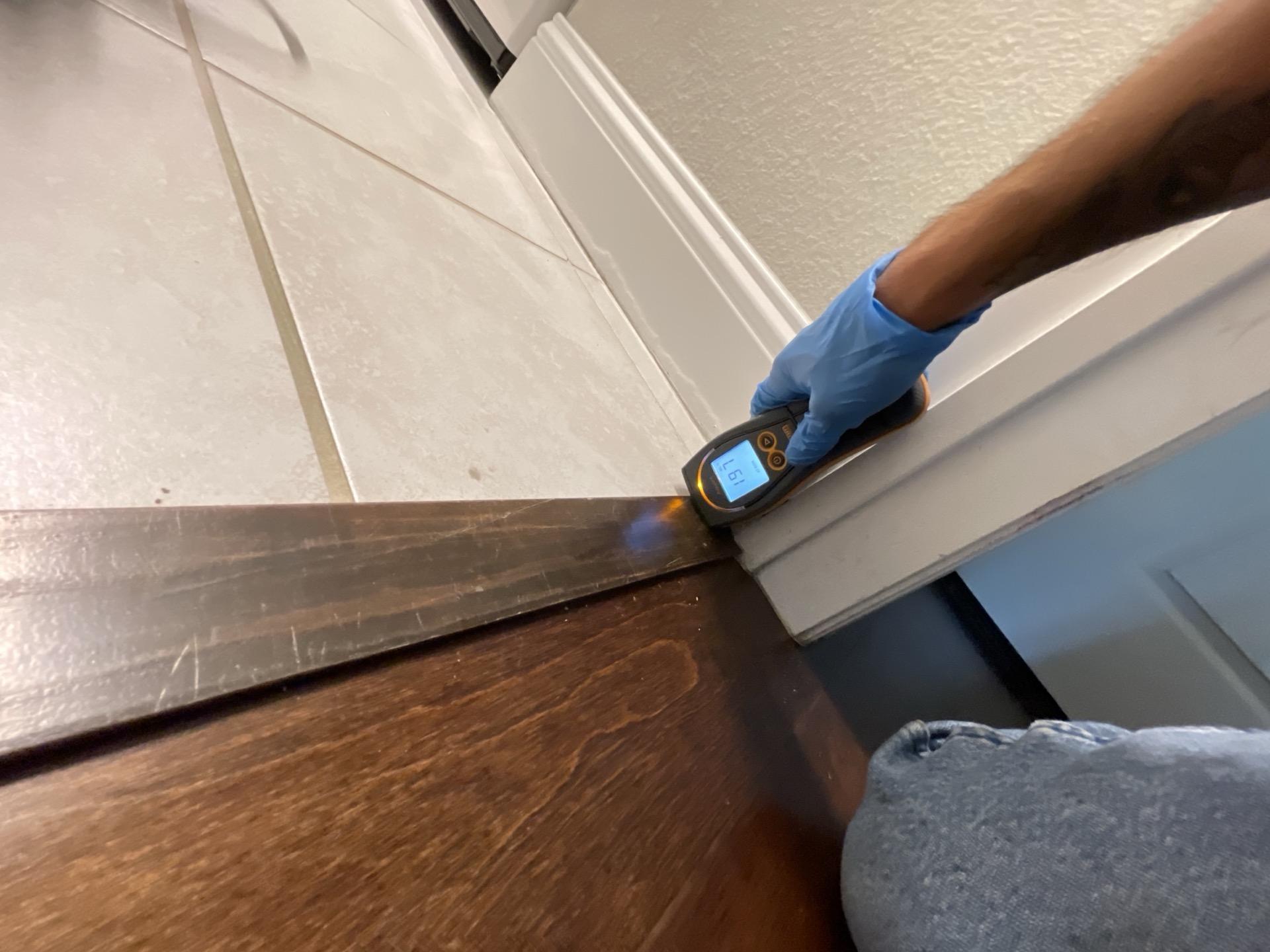 Moisture meter reading on laundry room baseboard after washing machine water damage