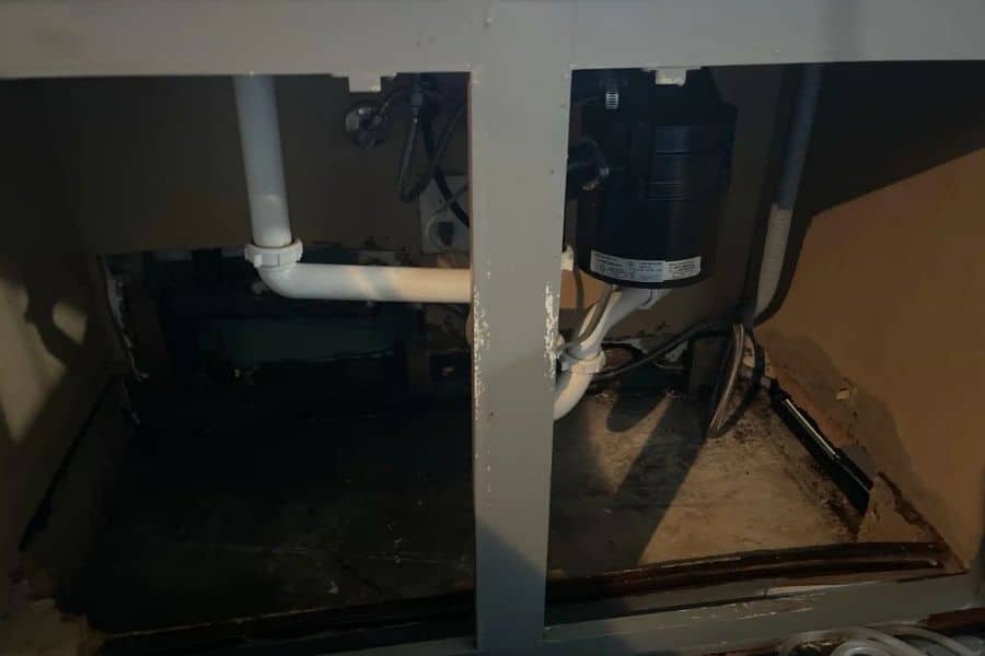 Water damage spreading from a sink leak beneath a kitchen cabinet in a North Texas home
