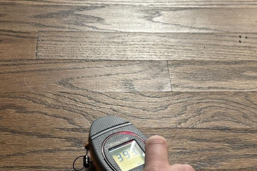 Technician using a handheld moisture meter to inspect a wall for hidden water damage in a Plano home