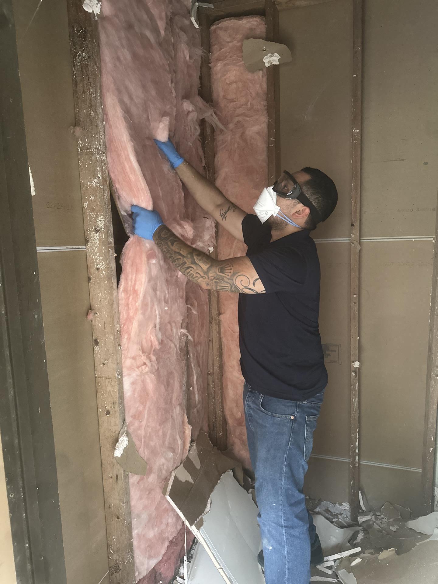 Wet drywall and insulation being removed from the closet framing