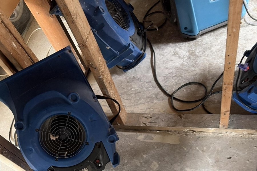 Air movers and a dehumidifier running during professional water damage drying in a Plano home