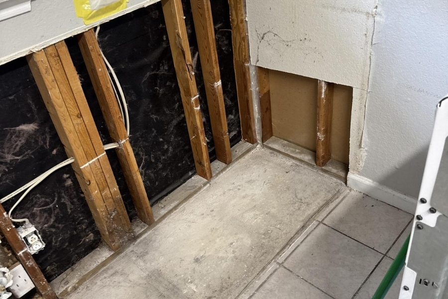 Technician removing water-damaged drywall and tile during restoration in a Plano home