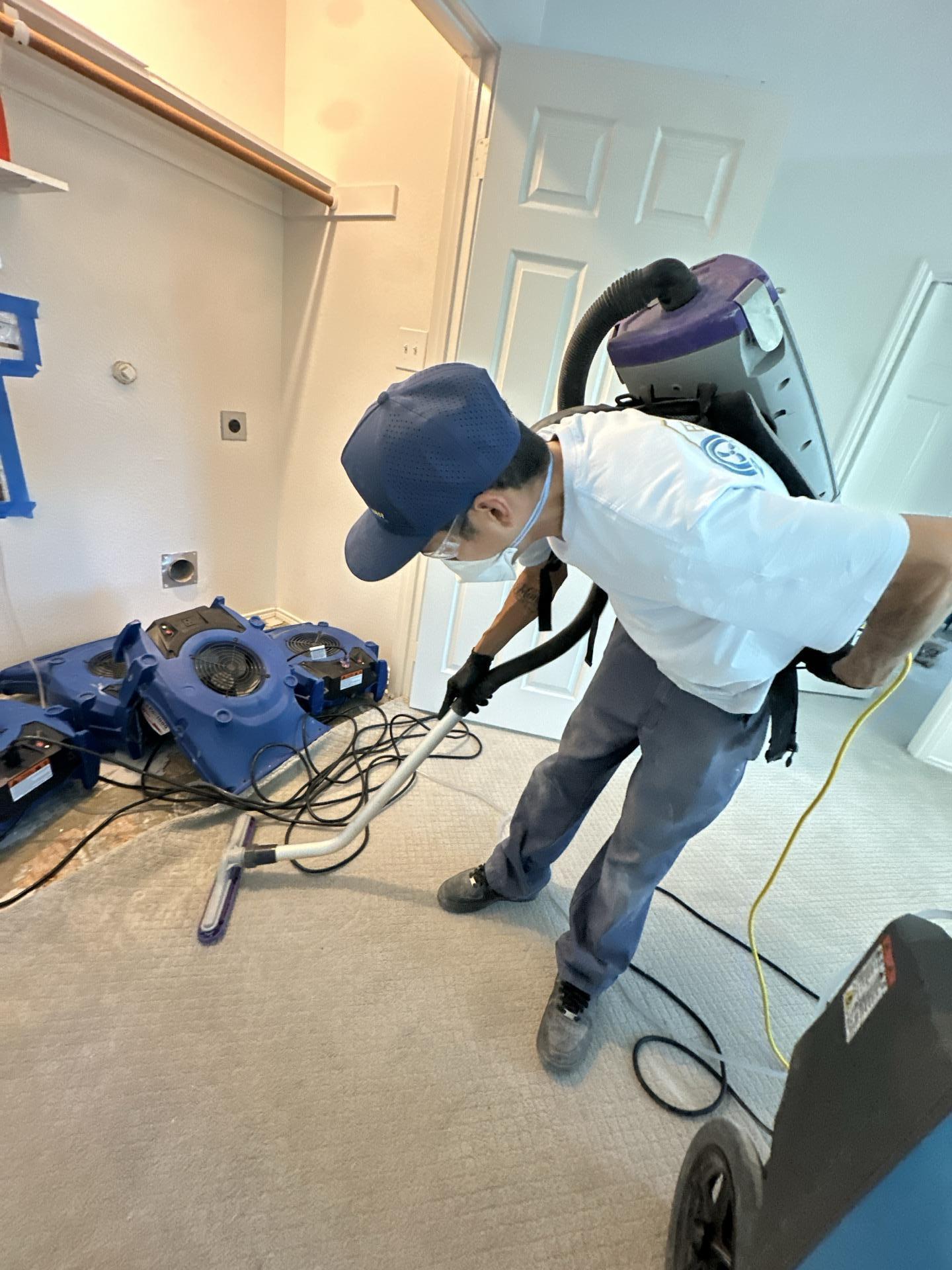 HEPA vacuuming the laundry room subfloor during water damage cleanup