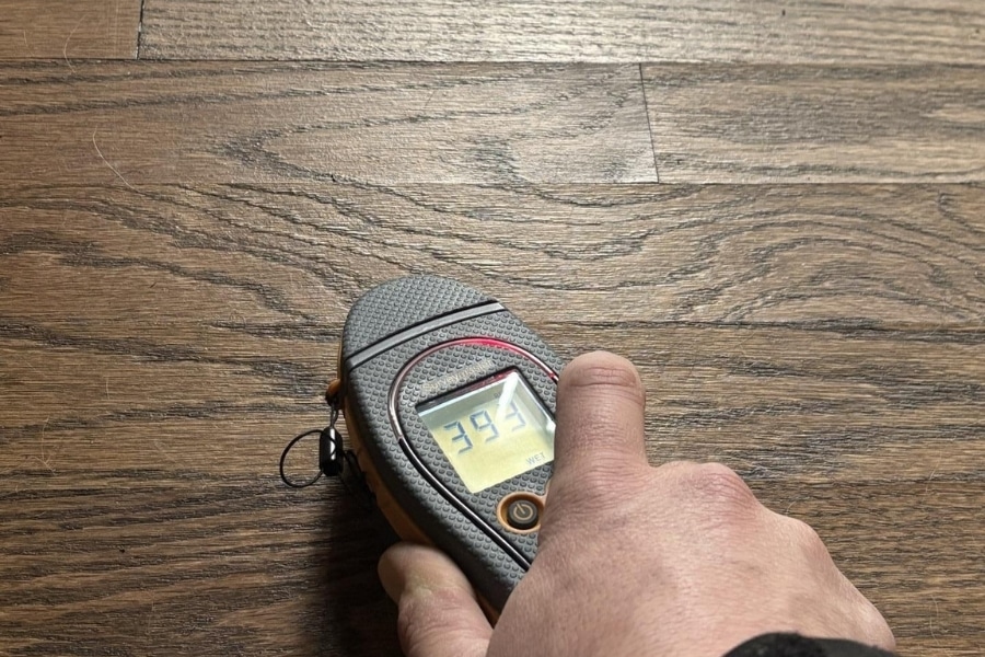 Restoration technician taking a moisture reading on a hardwood floor to check for hidden water damage