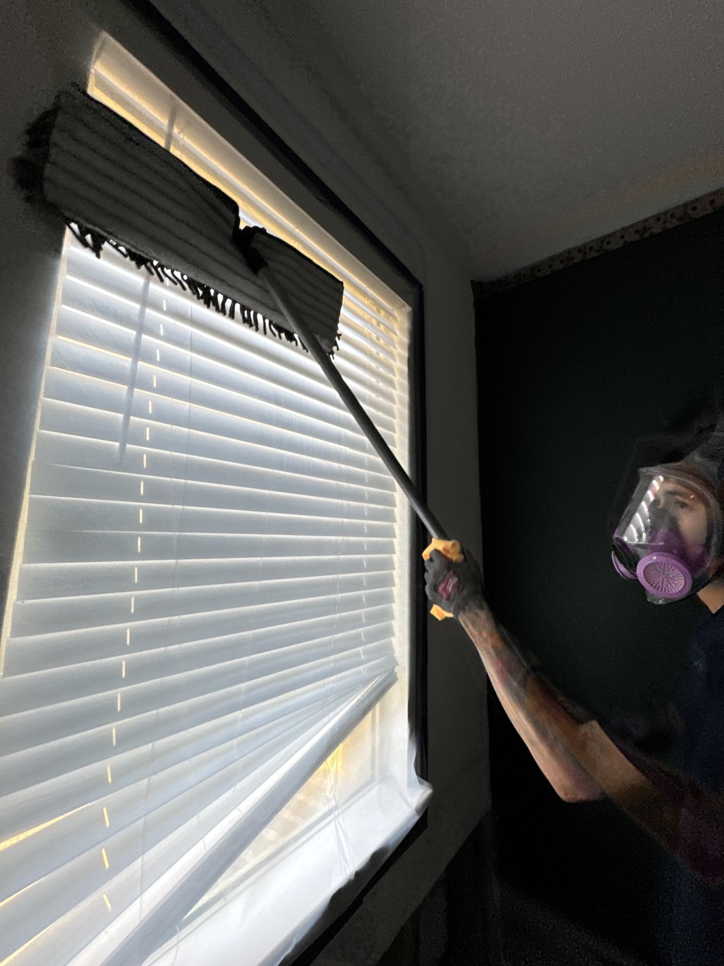 Technician cleaning blinds in the dining room during mold remediation